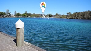 A waterfront view with a pier, a large marker, and a distant building complex. - Spinnaker Unit 201 (Forster)