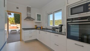 Une cuisine moderne avec des meubles blancs, un four encastré et un four à micro-ondes.