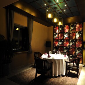 A dimly lit dining area with a table set for two, a floral-patterned partition, and hanging pendant lights. - XiannvshanHuabang (Chongqing)