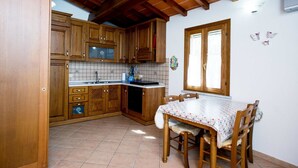 A kitchen with wooden cabinets, a tiled backsplash, a window, and a dining table with chairs.