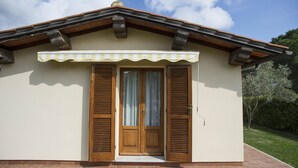 A small building with a beige facade, a brown roof, and a wooden door with shutters.