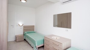 Ein Schlafzimmer mit Bett, Nachttisch, Kommode und einem an der Wand befestigten Spiegel.