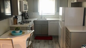 A compact kitchen with a microwave, stove, sink, and refrigerator. There is a dining table with chairs and a small plant on it. - ALL INCLUSIVE AMENITIES:Kayak,SUP,Pedal Boat,PingPong,Pickleball,Movie Nt &MORE! (Nice)