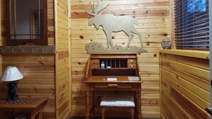 Una camera da chalet in legno con una scrivania, una sedia, una lampada e una mensola a parete.