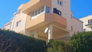 A multi-story residential building with a flat roof, balconies, and a clear blue sky. - Kike Apartments (Split)
