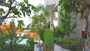 A staircase with a metal railing, surrounded by greenery and a stone wall. - Kike Apartments (Split)