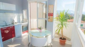 A modern kitchen with a dining area, a potted plant, and a view of the city. - Kike Apartments (Split)