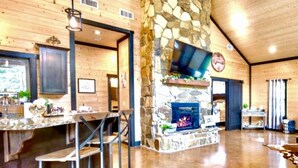 A spacious interior with a stone fireplace, wooden walls, and a bar area. - Romantic Cabin in Broken Bow! Secluded on 4+ acres, 1BR 2Bath, Hot Tub, FirePit (Broken Bow)