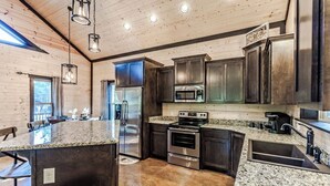 A modern kitchen with granite countertops, stainless steel appliances, and dark wooden cabinets. - Romantic Cabin in Broken Bow! Secluded on 4+ acres, 1BR 2Bath, Hot Tub, FirePit (Broken Bow)