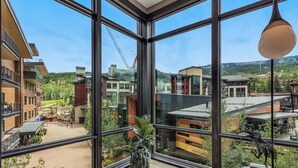 Ett modernt hotellrum med stora fönster som erbjuder utsikt över de omgivande byggnaderna och grönområdena.