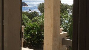 A view through a doorway of a coastal area with a stone column, greenery, and a distant body of water. - Chez Simone ( 6 pers.) (Ensuès-la-Redonne)