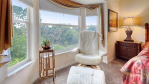 A bedroom with a large window, a chair, a bedside table, and a bed. - Corner 2-bed / 2-bath Unit #926, in the Stoneybrook Golf and Country Club (Sarasota)