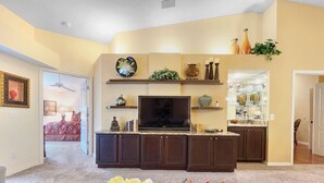 A living room with a TV, dark cabinets, a plant, and a vase on a shelf. - Corner 2-bed / 2-bath Unit #926, in the Stoneybrook Golf and Country Club (Sarasota)