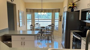 A kitchen with a dining area, a refrigerator, a microwave, and a sink. - Corner 2-bed / 2-bath Unit #926, in the Stoneybrook Golf and Country Club (Sarasota)