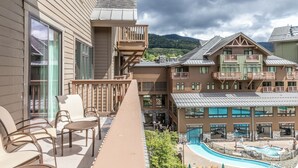 A hotel with a pool, outdoor seating, and a view of the mountains.