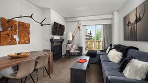 A modern living room with a fireplace, a dining area, and a balcony with a view.
