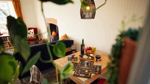 Una sala de estar acogedora con una mesa de madera lista para una comida, una silla roja y una estantería al fondo.
