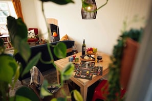 A cozy living room with a wooden table set for a meal, a red chair, and a bookshelf in the background.