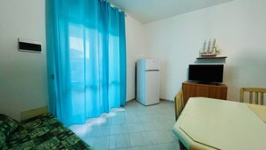 A small room with a bed, a table, a television, and a refrigerator. - Shardana 2 (San Teodoro)