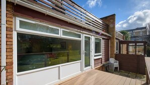 A residential property with a large sliding glass door, a wooden deck, and a brick exterior. - Corrin - Chic 1 Bedroom Apartment (North Berwick)