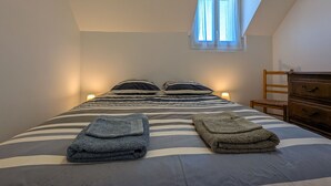 Una camera da letto con un letto, due lampade da comodino, un comò in legno e una finestra con tende.