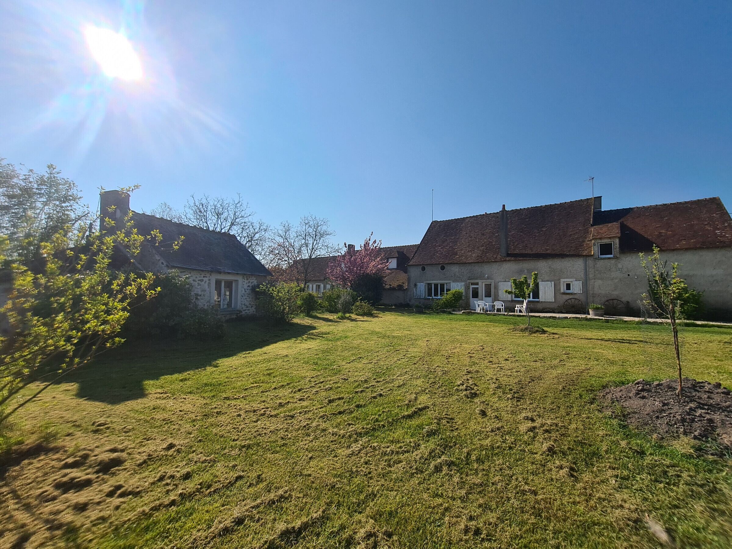 A courtyard with stone buildings, a grassy lawn, and a clear blue sky.