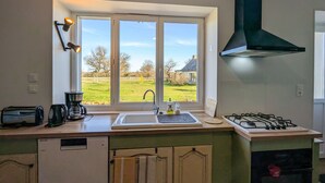 Una cucina con finestra, piano cottura a gas, lavello e macchina per il caffè.