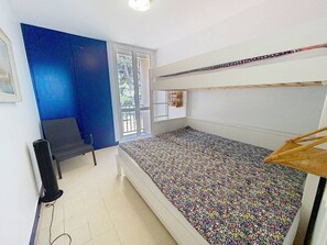 A room with a bunk bed, a desk, a chair, and a window.