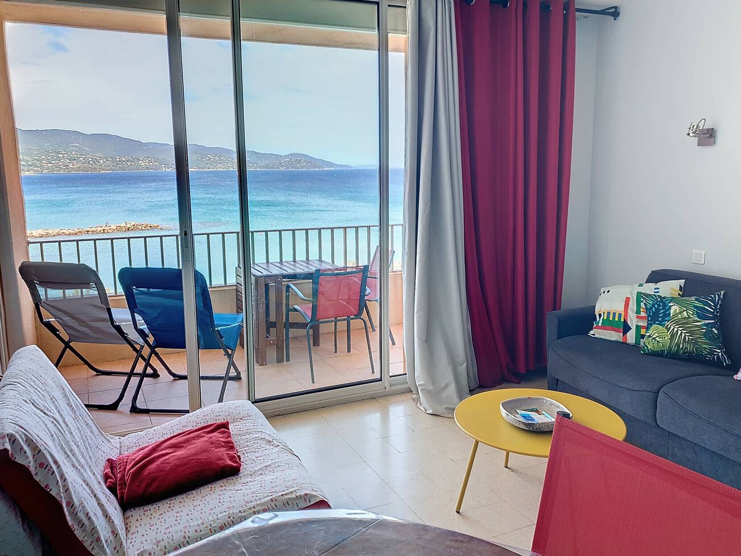 Un balcón con vistas al mar, un sofá, una mesita y una silla.