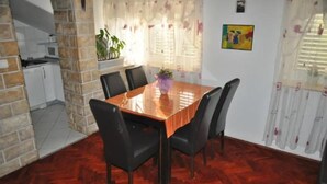 A dining area with a wooden table and black chairs, a kitchen in the background, and a window with curtains. - Park Apartment (Split)