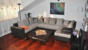 A modern living room with a sectional sofa, a dark coffee table, and a painting on the wall. - Park Apartment (Split)