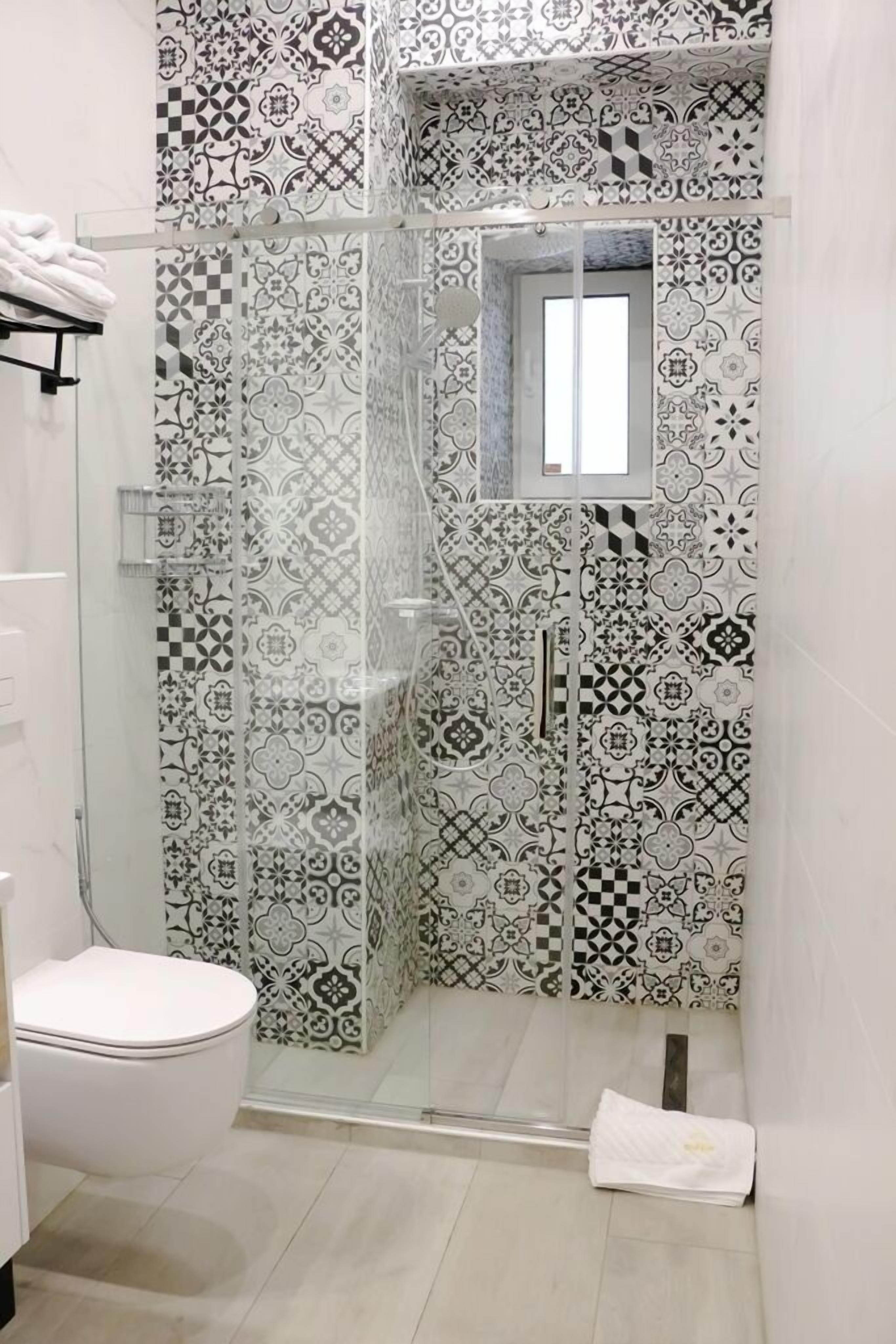 Ein Badezimmer mit Duschkabine, Toilette und Fliesen mit Muster.