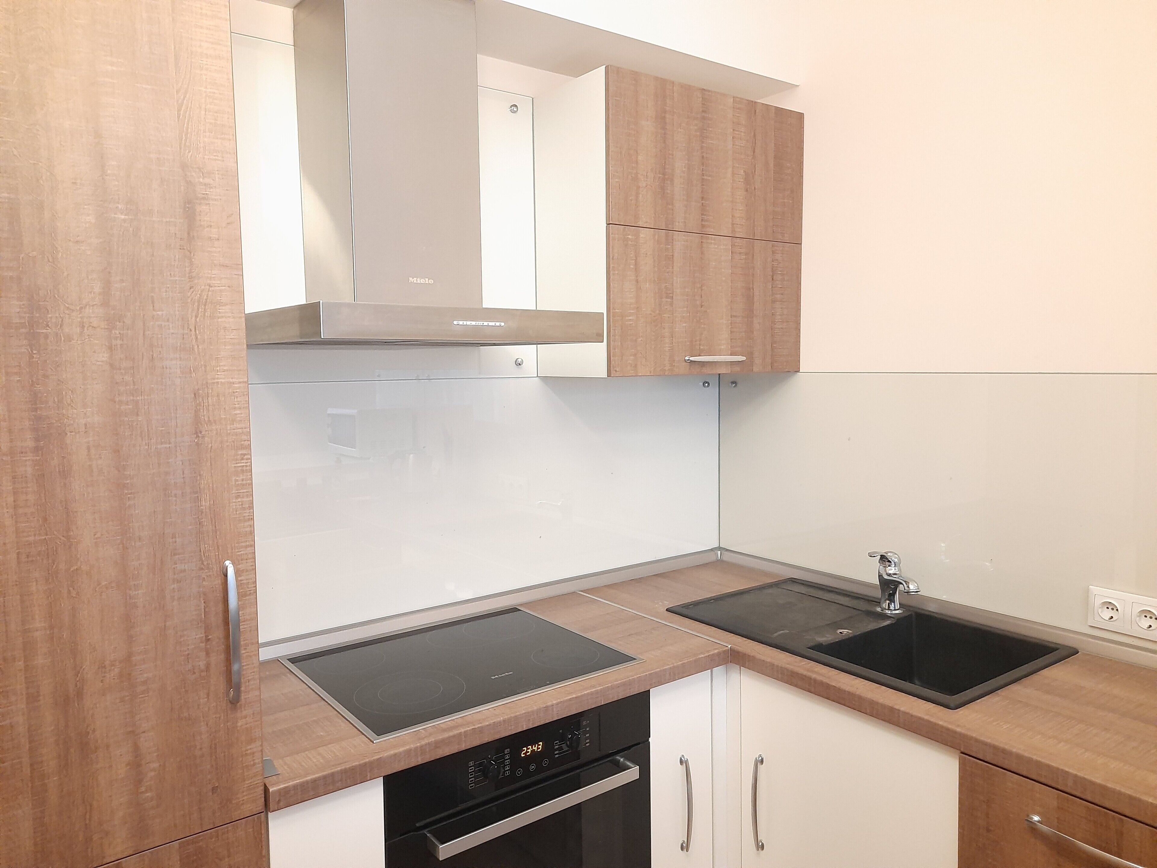 A modern kitchen with wooden cabinets, a stainless steel range hood, a double sink, and a dishwasher.