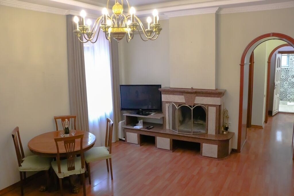 A living room with a wooden dining table, chairs, a television, and a fireplace.