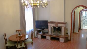 A living room with a wooden dining table, chairs, a television, and a fireplace.