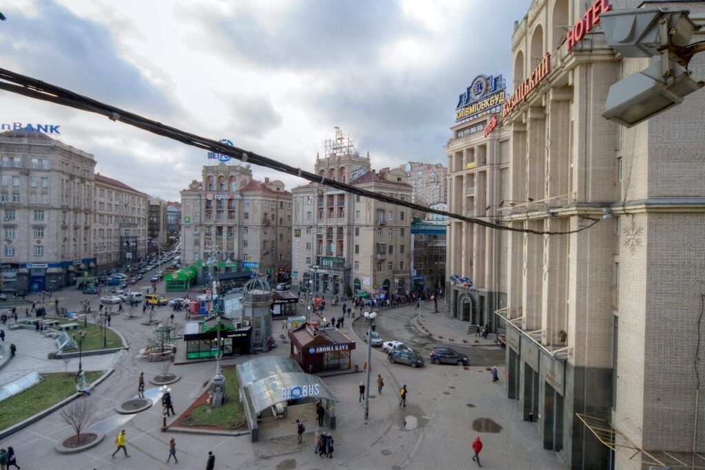Hotel amb un gran rètol, una plaça central amb una parada d'autobús i edificis adjacents amb diferents rèitols.