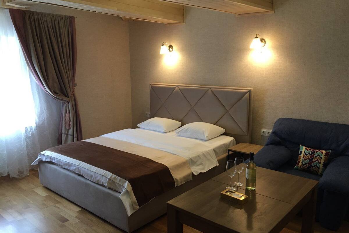 A hotel room with a large bed, two bedside tables, a sofa, and a wooden coffee table.