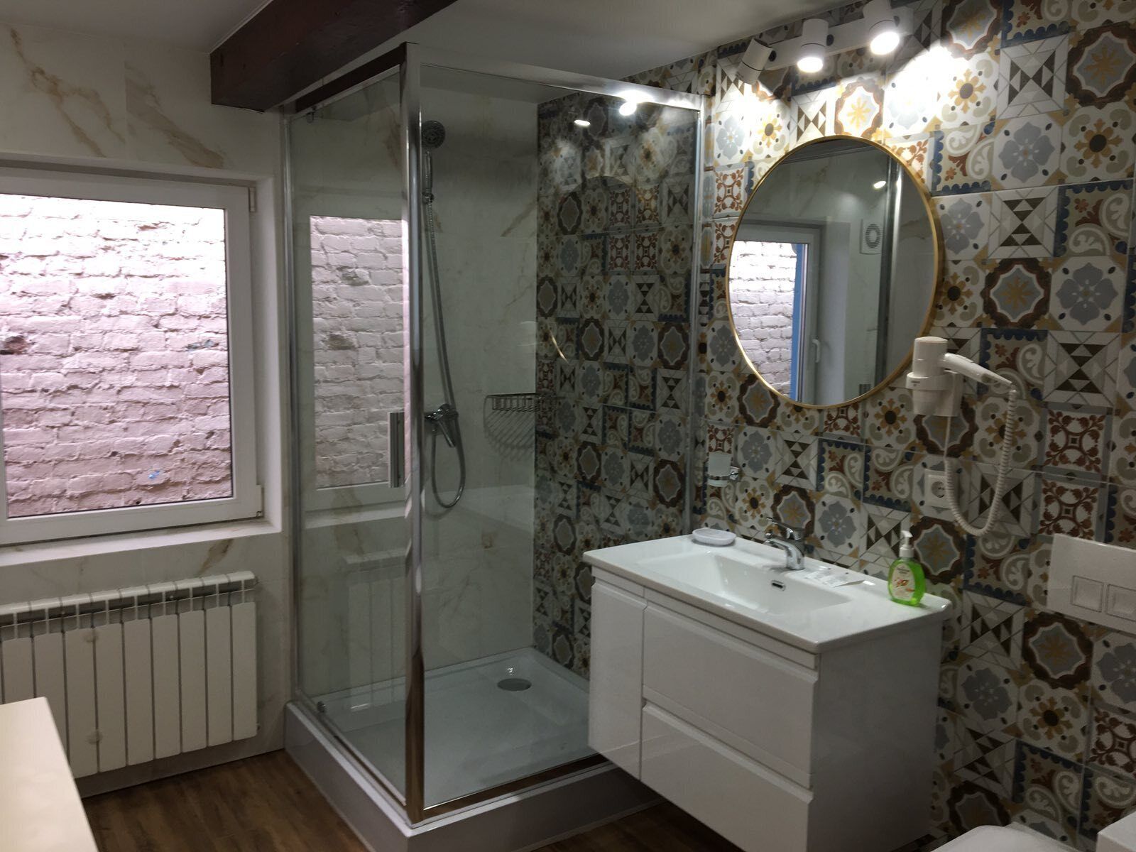 Une salle de bain avec une douche à parois de verre, un lavabo blanc et des carreaux décorés.