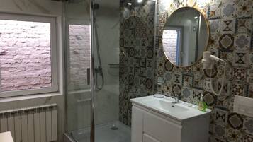 Une salle de bain avec une douche à parois de verre, un lavabo blanc et des carreaux décorés.
