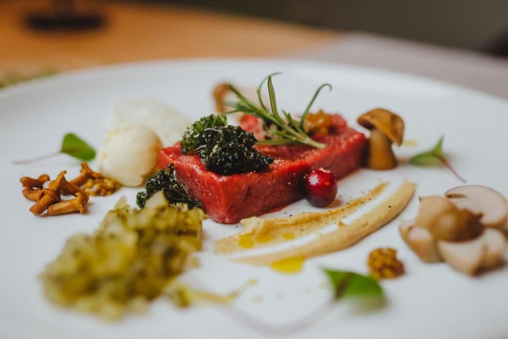 Un plato con un bistec, vegetales verdes y champiñones.