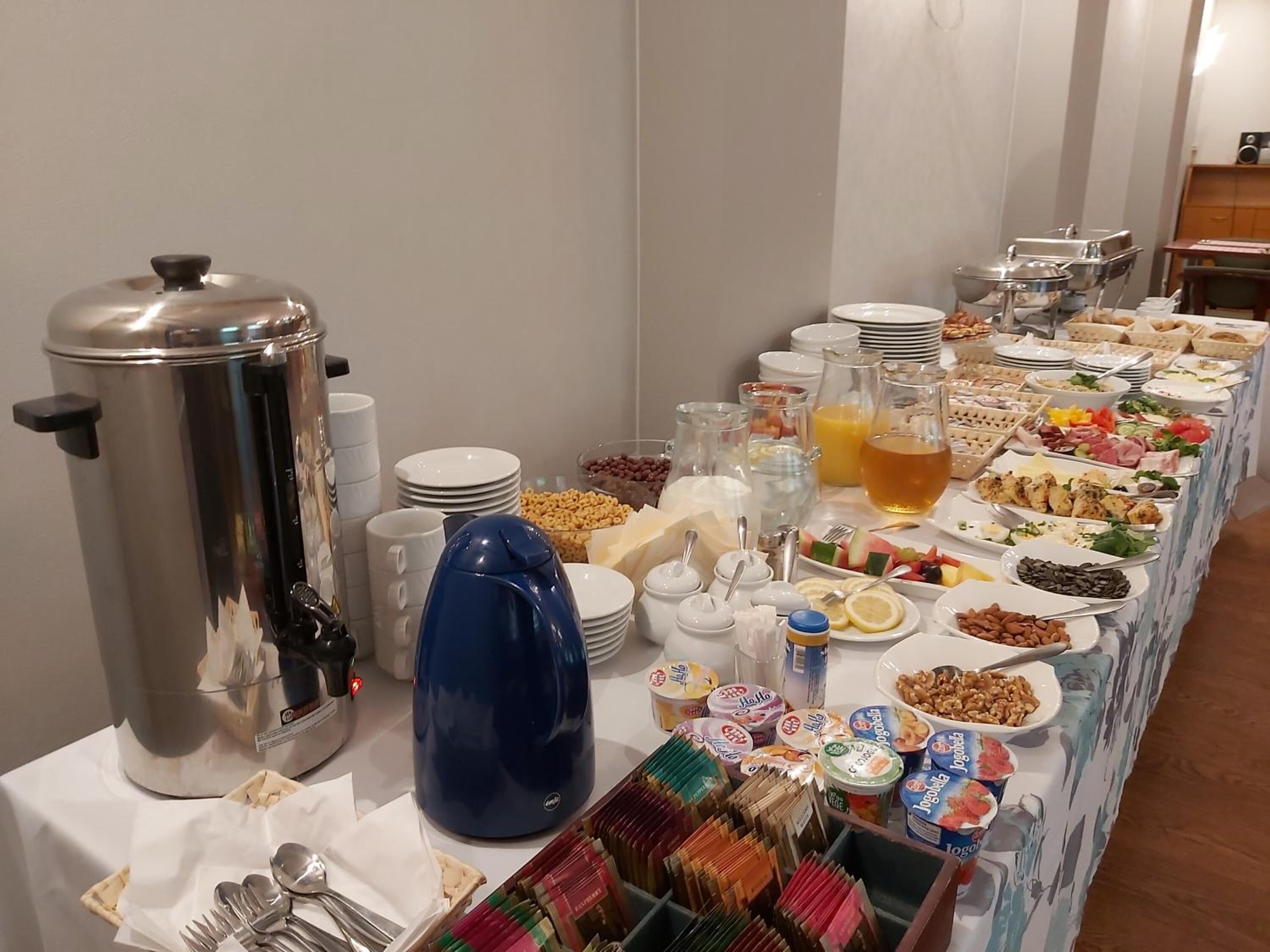 A buffet table with various food items, a coffee maker, and condiments.