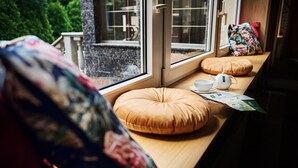 Asiento junto a la ventana con un cojín, un calentador de agua y una taza.