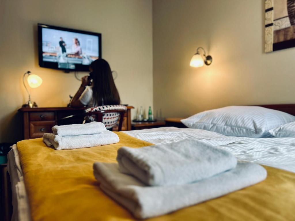 Une chambre d’hôtel équipée d’un lit, d’une télévision, d’une table de chevet et d’une lampe fixée au mur.