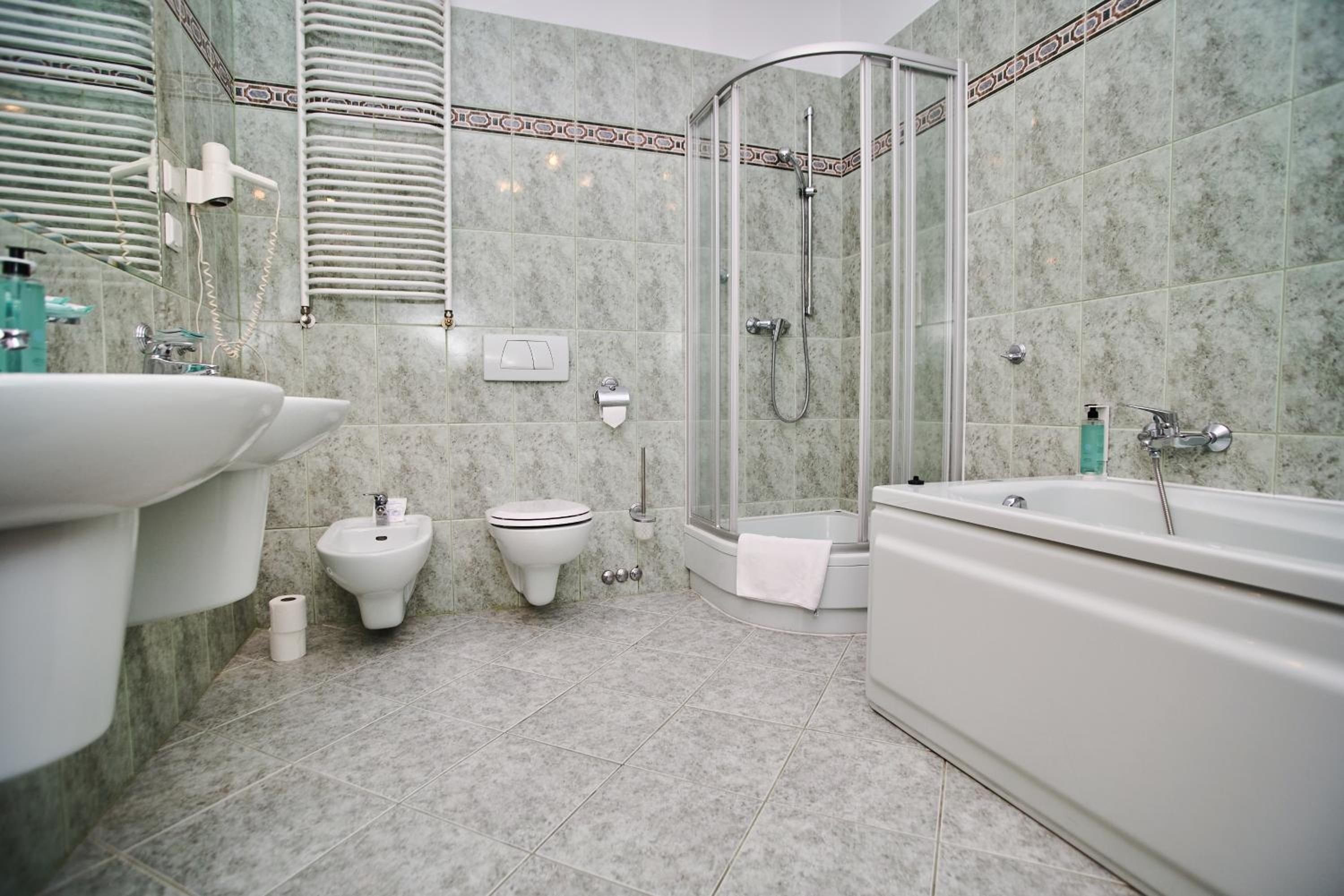 Een badkamer met douche, toiletgondel en bad.