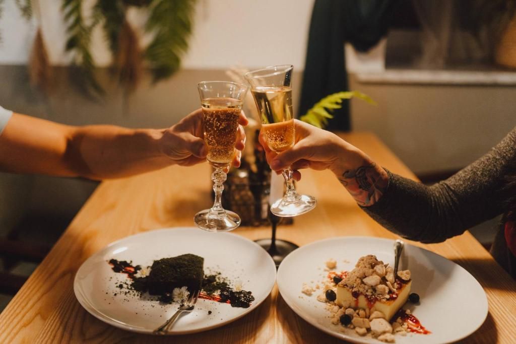 Deux personnes trinquent avec des coupes de champagne, une assiette avec un dessert et une bougie sur une table.