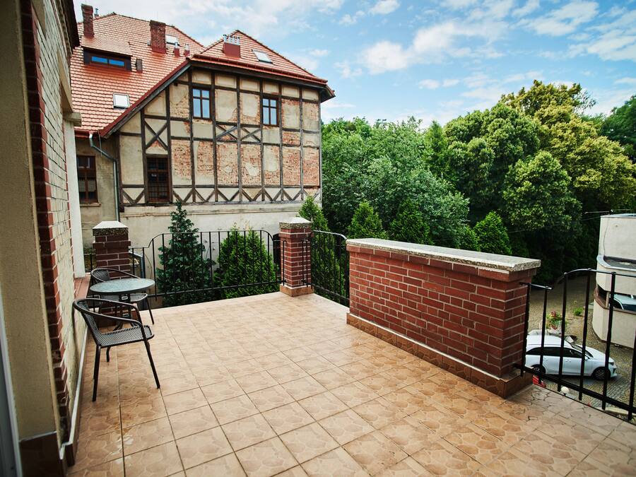 Un patio con suelo de baldosas, pared de ladrillo y valla de metal.