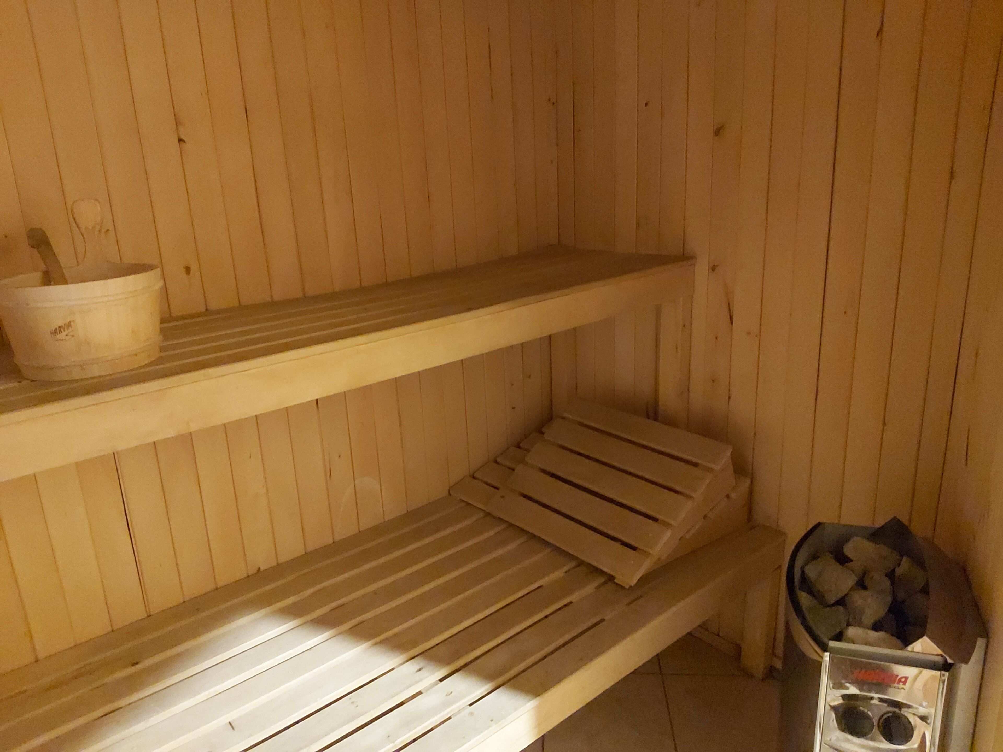 A sauna room with wooden benches and a stone basin.