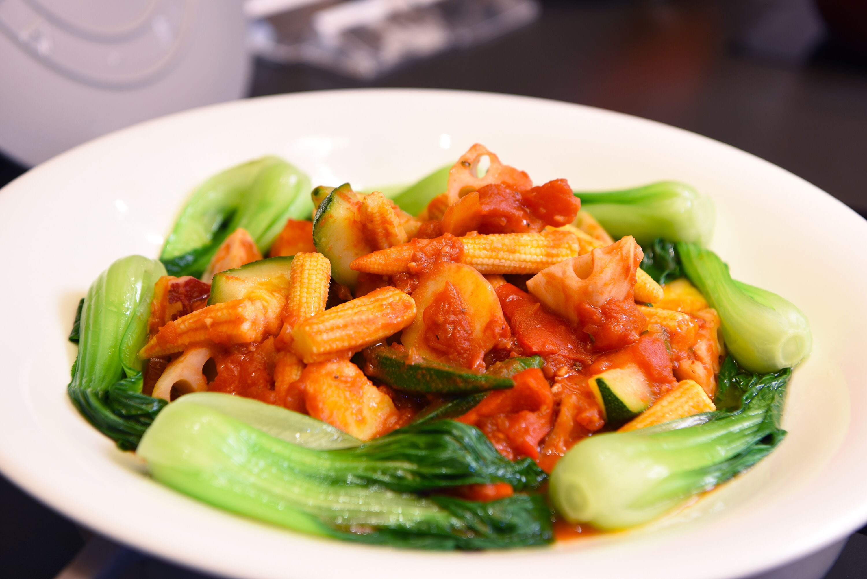 A plate of stir-fried vegetables including bok choy and corn.