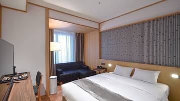 Een hotelkamer met een groot bed, een bureau met een computer, een stoel, een bank en een televisie.