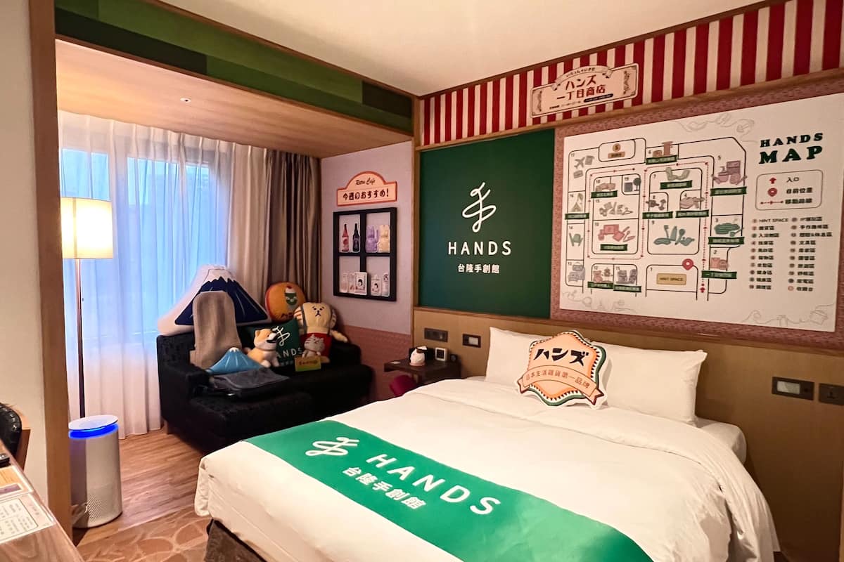 A hotel room with a bed, a map on the wall, and a sign above the bed.